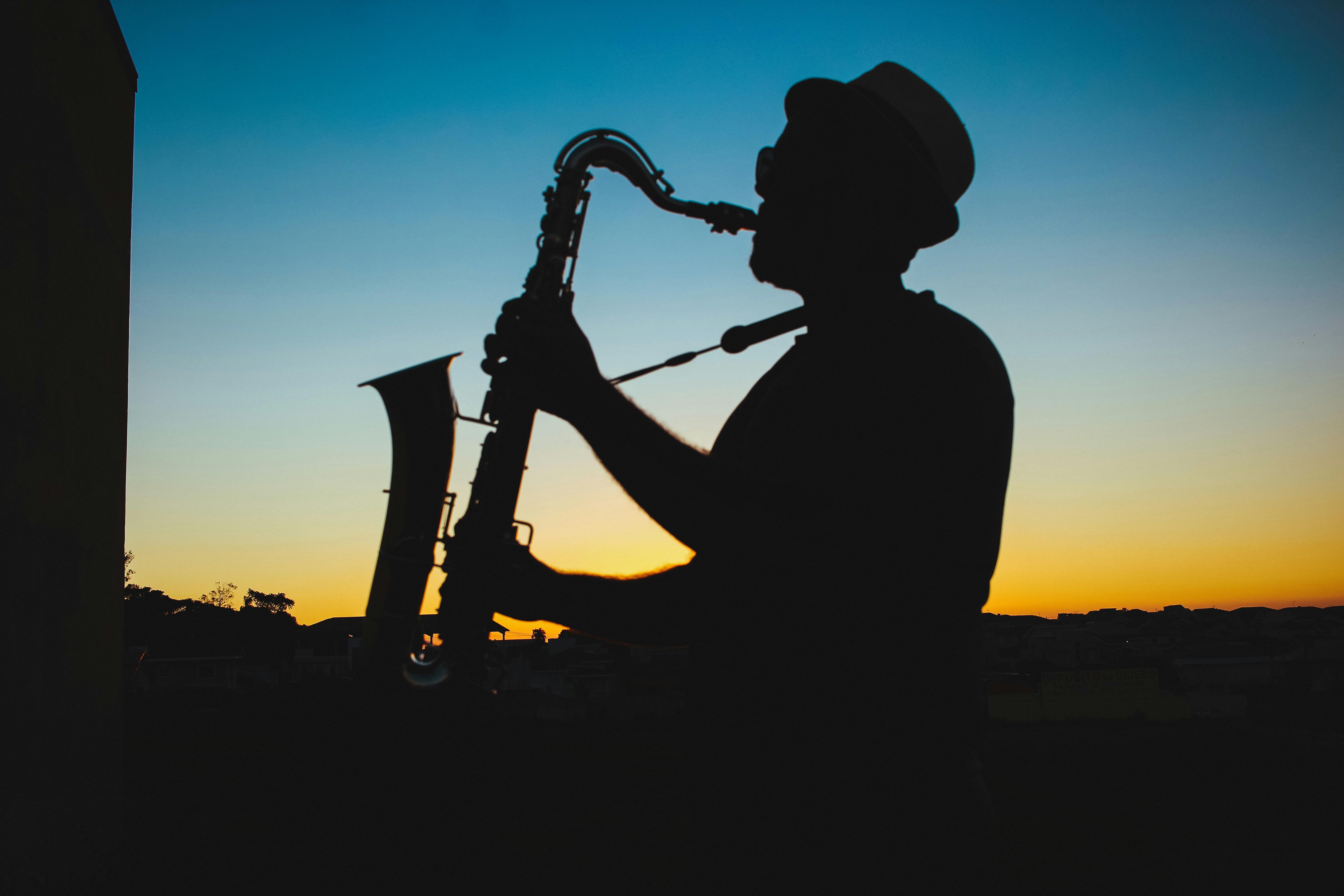 Silhouette of a saxophone player against a golden sunset sky